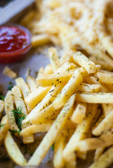 French fries with spicy seasoning in wooden plate on wooden broad.