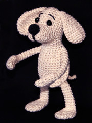 Handmade amigurumi knitted toy dog on black background close-up view