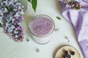 Obraz na płótnie Canvas Berry milkshake. Milkshake with blueberries on a white background, decorated with lilac flowers. Provence style