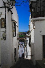 Typical narrow alley in traditional white village contrasting with dark blue sky - Arcos da la Frontera, Andalusia, Spain