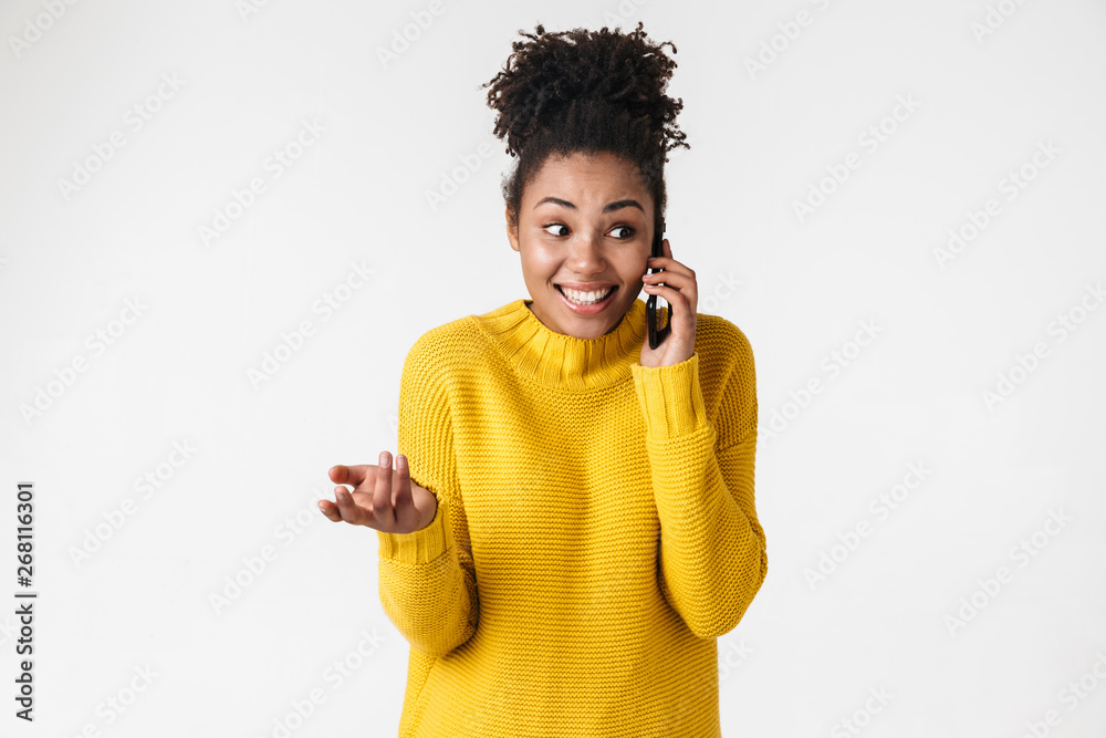 Canvas Prints Beautiful young african excited emotional happy woman posing isolated over white wall background talking by mobile phone.