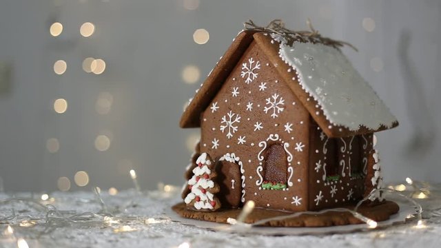 Handmade gingerbread house on the background of sparkling lights, decorated with snowflakes