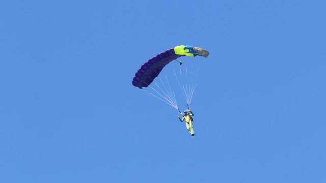 skydiver descends on a parachute wing type against a blue sky