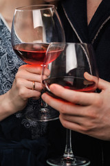 A couple, a man and a woman in bathrobes drink red wine from large glass goblets in the apartment. Kiss and hug.