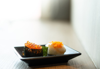 Ikura maki (or salmon roe maki) and hotate sushi (or scallop sushi) on the small Japanese style dish with copy space. Japanese food, raw food. Selective focus.