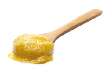 Yellow mustard sauce, spread with wooden spoon isolated on white background