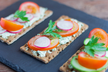 delicious summer sandwiches with cottage cheese with herbs and vegetables,sprinkle with flax seeds on a stone Board
