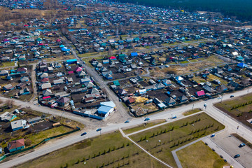 Naklejka premium Aerial view of a large number of small houses with colored roofs on the outskirts of a small provincial town of Lenin Kuznetsk on an spring sunny day with the road and cars