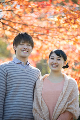 紅葉の前で微笑むカップル