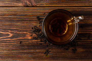 Cup of black tea on dark wooden background.