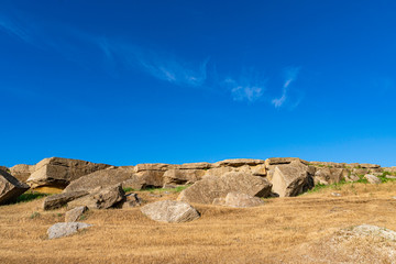 Small ancient rocks and dry yellow grass scenery