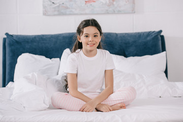 happy kid smiling while sitting in bedroom and looking at camera