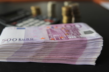 Euro banknotes, stacks of coins and a calculator in the background.