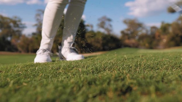 Golfer hitting a ball with iron down the course closeup slow motion