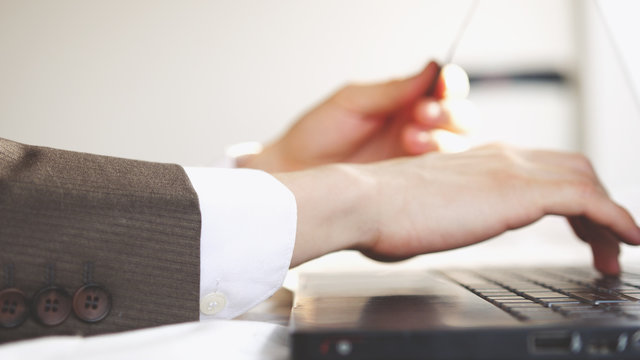 Man enters credit card information for online purchases while working on laptop