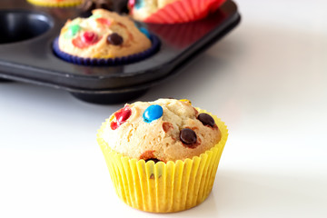 Homemade lemon muffins with colorful chocolate candy in paper case. White background. Selective focus.