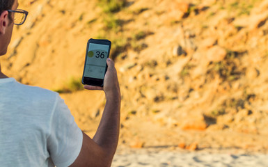 Young adult with Smart phone with weather forecast on screen, weather forecast high temperatures