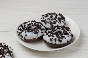 Donuts in a plate on white wood background, close-up