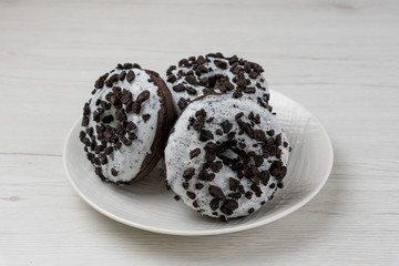 Donuts in a plate on white wood background, close-up