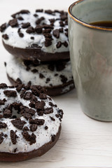 Donuts and coffee cup on a white wood background, close-up