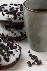 Donuts and coffee cup on a white wood background, close-up