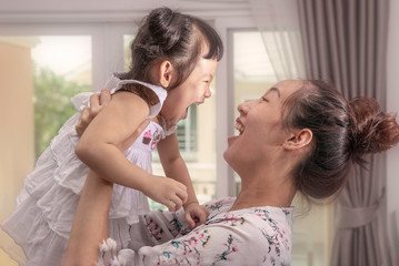 Mother lifting and playing with  girl baby.