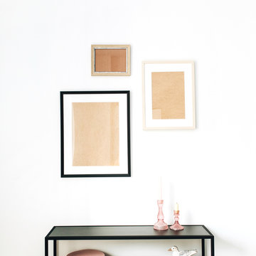 Modern minimal Scandinavian interior design concept decorated with mock up photo frames, bird figurine, rack on white background.