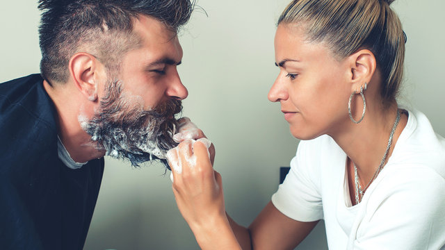 Barber paints beard and mustache in black color of hipster man in barbershop. Hairdresser washing beard to her handsome client. Cleaning beard Barbershop.