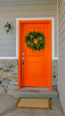 Vertical Home with a welcoming wreath hanging on the orange front door