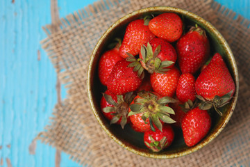 Imperfect fresh organic strawberries on blue rustic wooden background. Top view with copy space