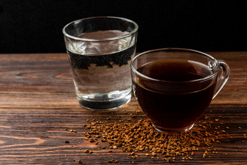 Cup of  coffee and water on dark wooden background.
