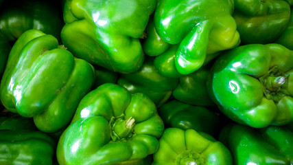 Obraz na płótnie Canvas Macro image of green bell peppers or paprica lying on counter in grocery store. Texture or pattern of fresh ripe vegetables