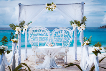 Beach wedding arch gazebo ceremonial decorated with white flowers on a tropical grand anse sand...