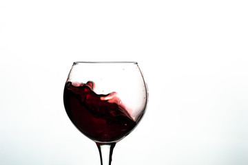 Red wine splash into glass on white background