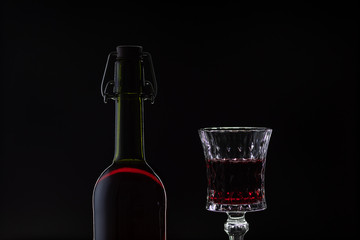 Rose wine. Red wine in bottle with wine glass over dark background. Silhouette