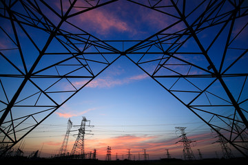 A silhouette of a high voltage tower at sunset