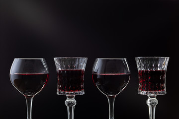 Rose wine. Red wine in four wine glasses over dark background with rays of light