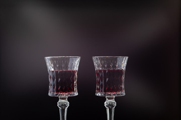 Rose wine. Red wine in two wine glasses over dark background with rays of light