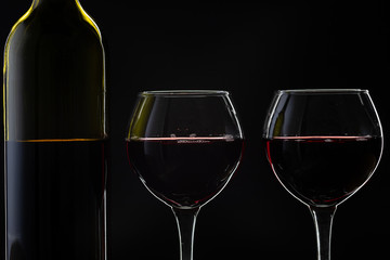 Rose wine. Red wine in bottle with two wine glasses over dark background