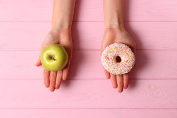 donut and apple in female hands. Healthy and unhealthy food. choice.