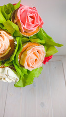 Closeup image of bouquet in red pot made from cupcakes against white wooden background. Beautiful shot of sweets and pastry over white background