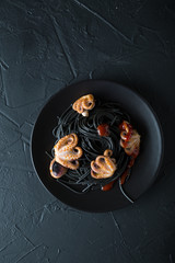 Black pasta with octopus on black background