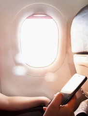 Woman hand using smart phone on the airplane