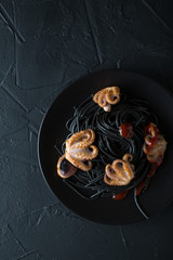 Black pasta with octopus on black background
