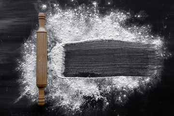 The process of making baking at home, flour and rolling pin are on a dark background.