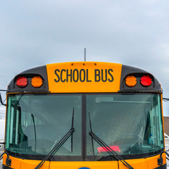 Clear Square Front view of a yellow school bus with homes and cloudy sky in the background