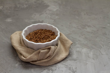 buckwheat in a white plate with a towel on a gray background. space for text. the view from the top