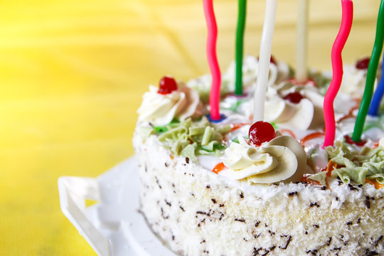 Traditional sweet birthday cake with colorful candles.