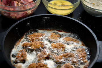 Crispy chicken being fried in boiling oil.
