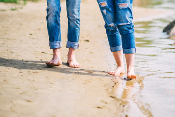 young barefoot couple walking along the beach. feet in the water summer